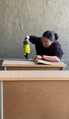 a woman sanding down some boxes on top of a wooden table next to a wall