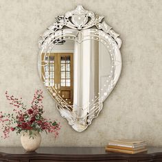 a mirror on the wall next to a vase with flowers