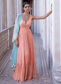 This look features a tangerine anarkali gown set. The v neck, sleeveless anarkali is embellished with gold sequin and mirror embroider. It further descends into a thick sequin & thread embroidered border. A contrast mint net dupatta with a scallop border and bootis completes the look. Cancan & pockets are included. Composition: Anarkali - Viscose georgette ,Dupatta - Soft net Care: Dry Clean Only and Vacuum Storage This product can be customised for colour, sleeves, length of blouse and neck des Sleeveless Anarkali, Scallop Border, Add Sleeves, Georgette Dupatta, Vacuum Storage, Indian Dresses Traditional, Anarkali Gown, Indian Wedding Wear, Embroidered Border