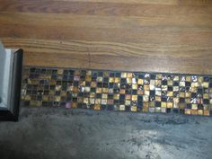 the floor is covered in gold and black mosaic tiles, along with an open toilet paper dispenser