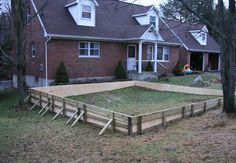 a backyard with a large wooden deck in front of a red brick house and trees