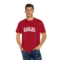 Show your Eagles pride with this classic t-shirt featuring bold, collegiate-style lettering. Perfect for game days, school events, or everyday wear, this tee lets you confidently represent your team. The clean and straightforward design makes it a versatile addition to any fan’s wardrobe. Cheer on the Eagles in style, and let everyone know who you’re supporting with this timeless team t-shirt. Collegiate T-shirt With Team Logo For Sports Events, College Fan Apparel T-shirt With Team Name, Varsity T-shirt With Team Logo For Football Season, College Varsity T-shirt With Graphic Print, Game Day Jersey T-shirt With Letter Print, Jersey T-shirt With Letter Print For Game Day, Sporty University Logo T-shirt With Crew Neck, Collegiate Game Day T-shirt With Team Name, University Red T-shirt With Team Name For Fans