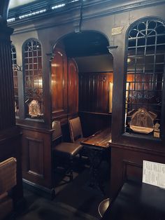 an old fashioned dining room with wood paneling and stained glass windows, along with leather chairs