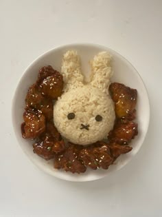 a white plate topped with meat and veggies covered in bunny shaped rice krispy kreme