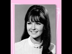 an old black and white photo of a woman with long hair smiling at the camera