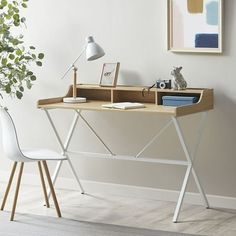 a wooden desk with a white chair next to it and a painting on the wall