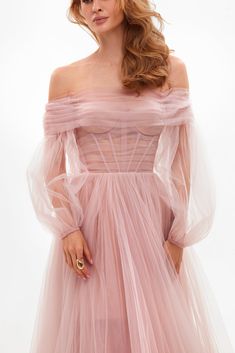 a woman wearing a pink dress with long sleeves and an off the shoulder neckline