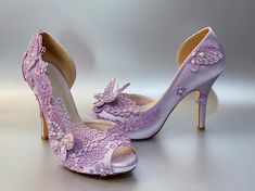 a pair of purple high heeled shoes with flowers on the side and butterfly detailing