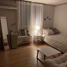 a bed room with a neatly made bed sitting next to a table and chair in front of a window