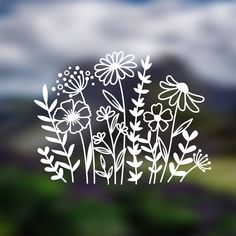 a window with flowers drawn on it in front of a cloudy sky and green grass