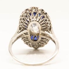 The Mila ring is a handmade engagement ring. It centers one antique oval very rare, elongated diamond of D color, SI2 clarity that weighs 1.72ctw. The center stone is surrounded by 22 natural calibrated French cut sapphires that weigh 2.50ctw. Thirty old mine cut diamonds of H color VS1 clarity that weigh 1.30ctw surrounded the sapphires in a second halo. This ring is currently size 8 and can be sized. Ring measurement: 23mm by 14mm Total weight: 3.9 dwt/ 6.1 grams Oval Halo Ring With Multi-stone Diamond, Diamond White Multi-stone Oval Diamond Ring, Classic Oval Sapphire Ring With Rose Cut Diamonds, Oval Multi-stone Diamond Ring In Diamond White, Oval Multi-stone Diamond White Diamond Ring, Oval Multi-stone Sapphire Ring In Platinum, Oval Halo Ring With Rose Cut Diamonds For Anniversary, Art Deco Oval Cabochon Wedding Rings, Platinum Oval Cabochon Ring With Center Stone