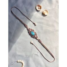 a necklace and earring laying on top of a white cloth covered table next to seashells