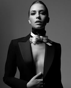 a woman wearing a black suit and bow tie