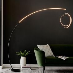 a living room with a green couch and a black wall behind the lamp is a circular light fixture