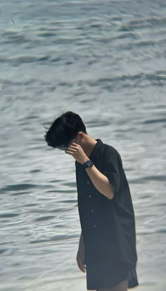 a man standing in the water covering his face