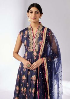 This enchanting ensemble features a floral print with intricate border embroidery. The anarkali kurta, paired with a matching dupatta adorned in sequins and gold thread, exudes elegance and charm. The plain churidar complements the set, adding a touch of feminine grace and sophistication. Perfect for any special occasion. Anarkali Style Indigo Wedding Sets, Indigo Chanderi Salwar Kameez With Resham Embroidery, Blue Floral Chanderi Kurta, Festive Anarkali Churidar With Floral Embroidery, Indigo Anarkali Sets With Resham Embroidery, Blue Anarkali Set With Floral Embroidery For Eid, Blue Floral Print Anarkali Set For Navratri, Indigo Anarkali Dupatta With Zari Work, Blue Floral Embroidered Anarkali Set For Eid