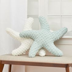 two starfish pillows sitting on top of a wooden bench in front of a window