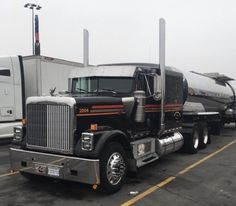 a large semi truck parked in a parking lot next to other trucks and tankers