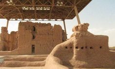 an adobe building in the desert under a roof