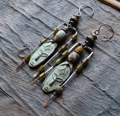 two pairs of earrings with beads hanging from them on a piece of wooden table next to a pair of scissors