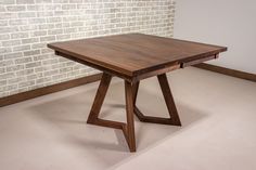 a wooden table sitting on top of a white floor next to a brick wall in an empty room