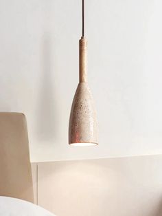 a light that is hanging from the ceiling in a room with a bed and chair