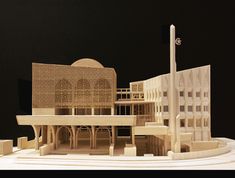 a model of a building made out of wood on a white table with black background