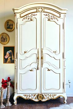 an ornate white armoire with gold trim