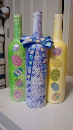 three bottles with designs on them are sitting on a counter next to each other, one has a blue bow