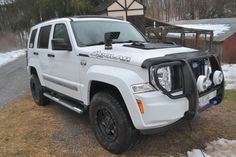 a white jeep parked on the side of a road next to snow covered ground and trees