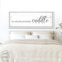 a bed with white sheets and pillows in front of a wooden sign that says, we should probably probably cuddle