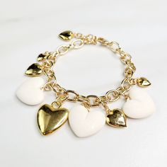 Vintage hearts are the focal point of this love filled bracelet. An assortment of gold plated hearts and matte ivory hearts play along the edge, perfect as a gift for someone you love. Handmade in the United States, a matching necklace and earring set are available. Features: - Gold Plated Vintage Hearts - Matte Ivory Vintage Hearts - Gold Plated Mixed Cable Chain - Lobster Claw Clasp - Extension - Handmade in the United States Dimensions: - Length: 7.5" - Extension: 1" - Total Length: 8.5" Gold-tone Metal Jewelry With Heart Charm, Elegant White Charm Bracelet With Heart Charm, White Heart Pendant Jewelry With Heart Charm, White Heart-shaped Jewelry Gift For Her, White Heart Shaped Jewelry With Heart Beads, White Heart-shaped Jewelry With Heart Charm, White Jewelry With Heart Beads, White Heart-shaped Metal Charm Bracelet, Elegant White Heart Charm Bracelet