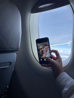 a person taking a photo on their cell phone while flying in an airplane with the window open