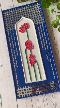 a blue and white card with red flowers on the front, sitting on a wooden table