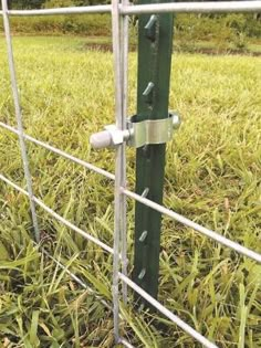 a close up of a metal fence with grass in the background