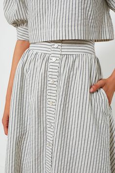 The Linen Stripe Cora Skirt is perfect for countless occasions. Featuring a center button placket detail, side seam pockets, and a side seam zipper, this piece will make you feel elevated and as breezy as the wind by the water. Pair as a matching set with the Linen Stripe Edie Top for an elevated weekend look or with a white top and cardigan for your everyday office outfit. High rise Center button placket detail Side seam pockets Side seam zipper Midi length Unlined A-line Shape Material: 100% L Chic Summer Skirt With Buttoned Pockets, Long Skirt Bottoms With Button Closure For Workwear, Long Skirt With Button Closure For Work, Casual Skirt With Button Cuffs For Work, Spring Long Skirt With Buttons, Flowy Skirt Bottoms With Button Closure, Chic Flare Bottoms With Buttons, Chic Flared Skirt Bottoms With Buttons, Workwear Long Skirt With Button Closure