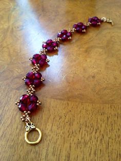 the necklace is made with red glass beads and gold plated metal clasps on a wooden table