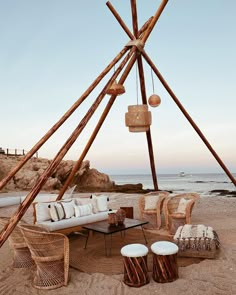 an outdoor seating area on the beach with chairs, tables and stools around it