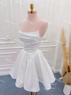 a short white dress on display in front of a mannequin headdress