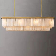 a rectangular chandelier hanging from a ceiling fixture in a room with grey walls