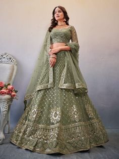 a woman in a green lehenga standing next to a chair