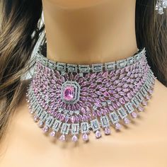 This majestic pink zirconia choker set is a stunning blend of heritage and modern style.  Imagine stepping into a grand event, adorned in this meticulously handmade necklace set, where every stone sparkles brilliantly, catching the light with each movement. The intricate design, featuring a necklace, earrings, and maang tikka, exudes elegance and royalty, inspired by the rich tradition of Indian craftsmanship. The pink zirconia stones, paired with shimmering silver accents, offer a contemporary Diamond Gemstone Jewelry For Reception, Reception Diamond Gemstone Jewelry, Cubic Zirconia Gemstone Jewelry For Reception, Luxury Diamond Choker Jewelry, Elegant Pink Necklace With Jewels, Elegant Pink Jeweled Necklaces, Luxury Pink Crystal Jewelry, Luxury Wedding Choker, Elegant Pink Bridal Sets As Gift