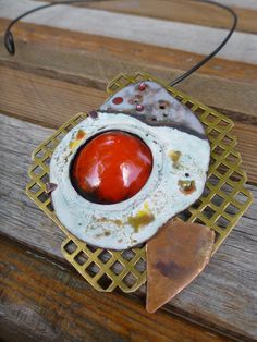 a red and white object sitting on top of a piece of wood next to a wire