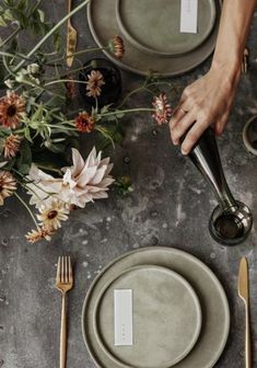 a table setting with place cards and flowers on the plates, silverware and cutlery