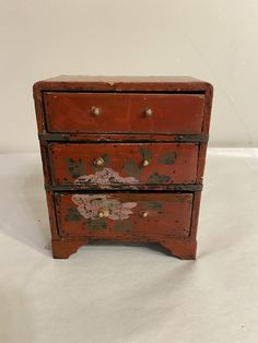 an old red painted dresser with gold knobs on the top and bottom drawer open