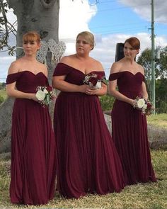 three bridesmaids standing in front of a grave with their dresses pulled back and flowers in their hair