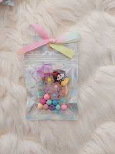 a clear bag filled with lots of colorful candies on top of a white furry surface