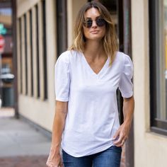 Introducing the Amaryllis Women's V-Neck Puff Sleeve Tee, where casual meets elegance. This tee features a flattering V-neckline that enhances the neckline, while the puff sleeves with gathered shoulder detail add a stylish and feminine touch. Made from soft stretch fabric, this tee provides comfort and ease of movement, making it an ideal choice for everyday wear. The relaxed fit ensures it pairs effortlessly with jeans or skirts for a versatile look. Whether you're running errands or meeting f White V-neck Puff Sleeve Top For Day Out, Casual V-neck Cotton Puff Sleeve Top, Feminine Cotton Puff Sleeve Top With V-neck, Chic V-neck Puff Sleeve Top For Day Out, White V-neck Top For Casual Gatherings, Fall V-neck Puff Sleeve Top For Day Out, Fall V-neck Puff Sleeve Top, Fitted Short Sleeve V-neck Top For Day Out, Trendy V-neck Short Sleeve Top For Day Out