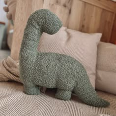 a stuffed dinosaur sitting on top of a bed