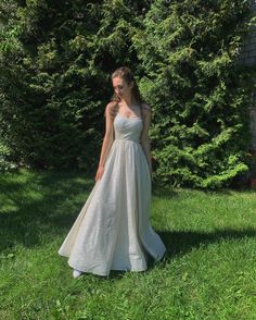 a woman is standing in the grass wearing a dress